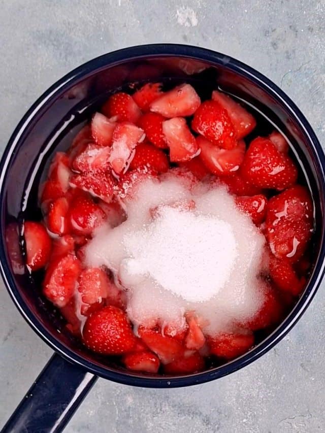 kattilassa mansikoita vedessä ja sokerikeko. 