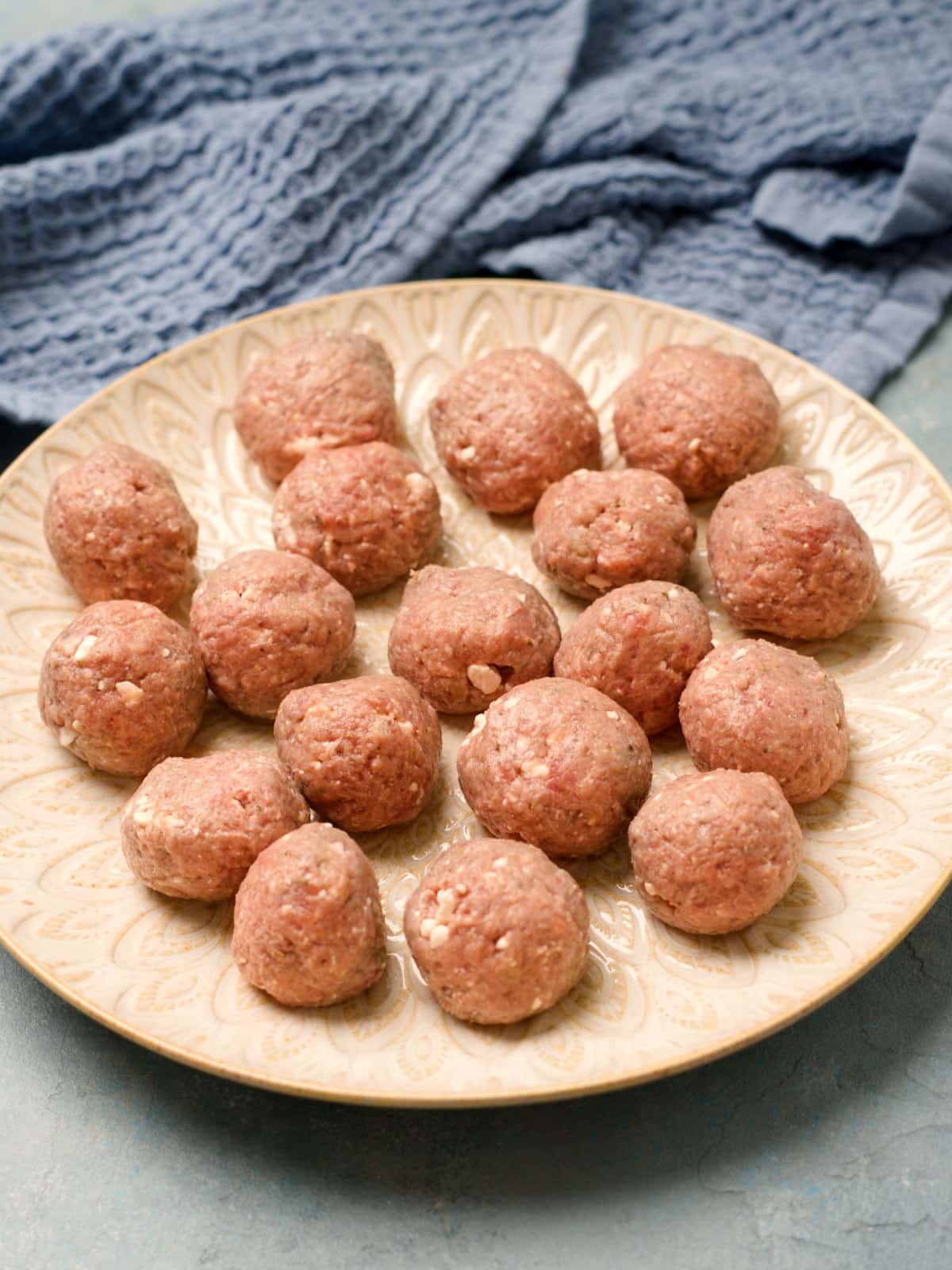 Pyöritellyt raat lihapullat lautasella. 